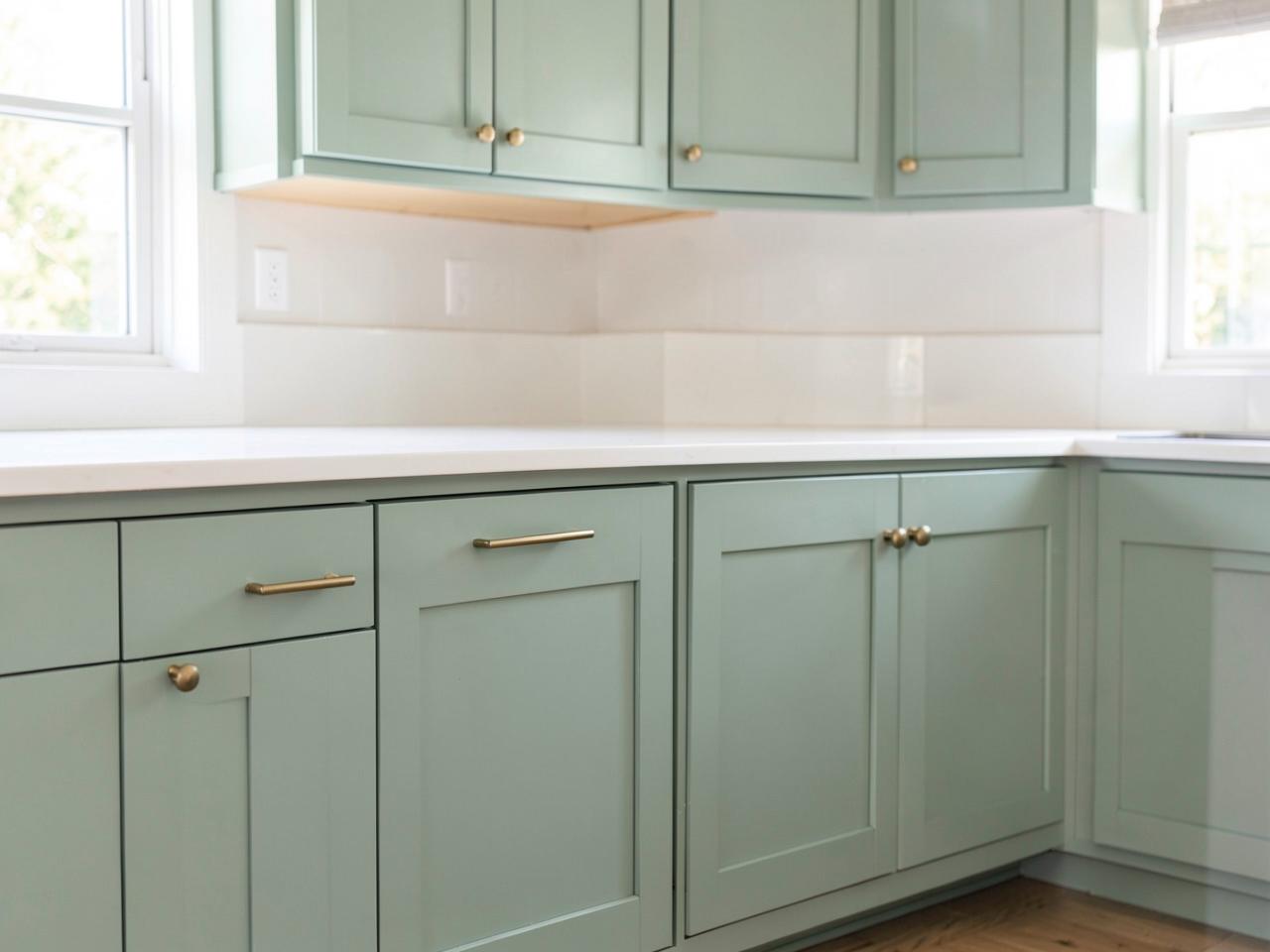 Kitchen cabinets freshly refinished in soft sage green with brass hardware