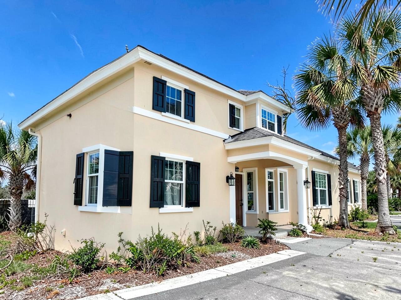 Coastal Texas home exterior freshly painted in pale sand with dark shutters